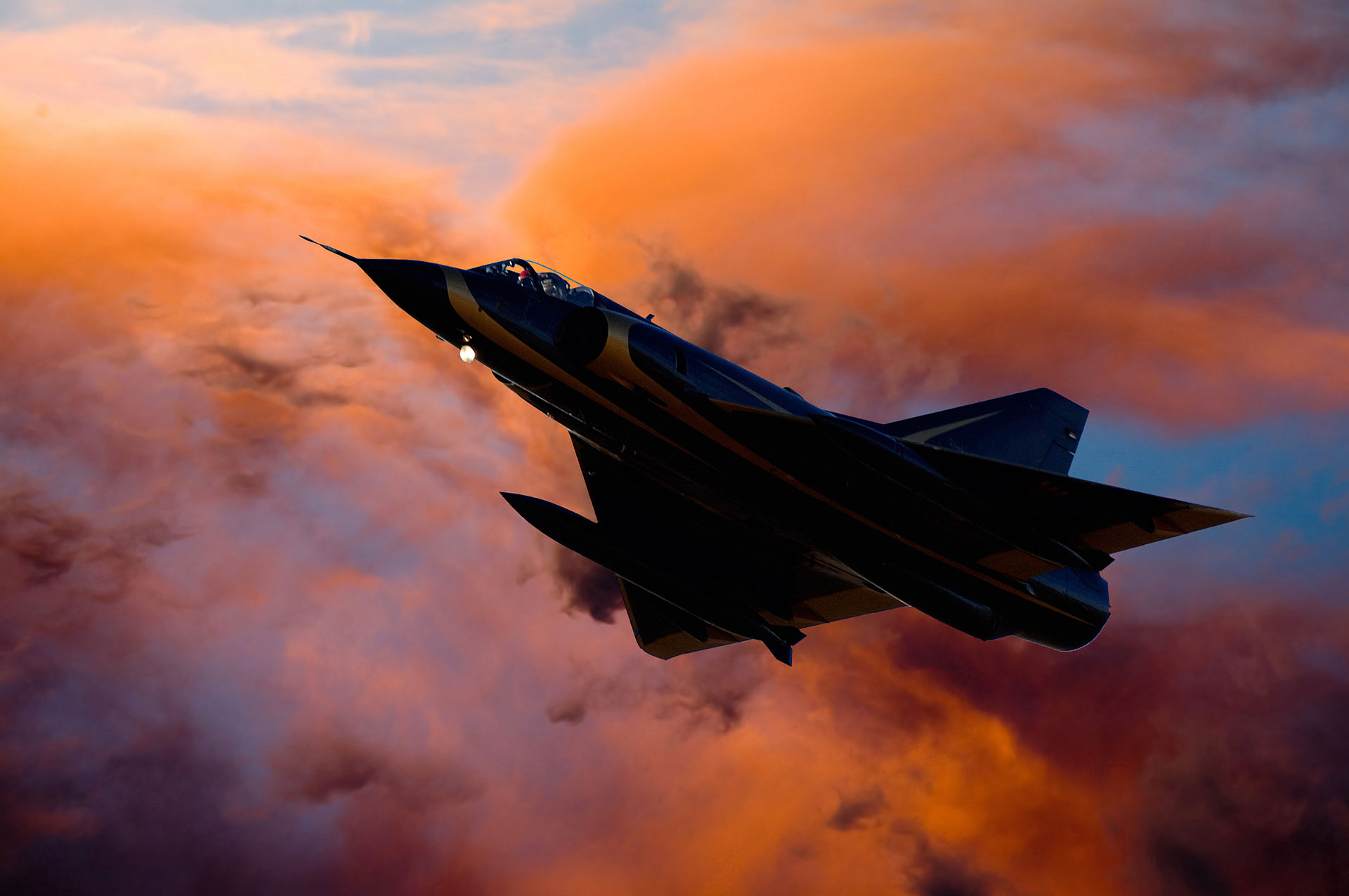 Fighter jet climbing through dramatic sunset clouds