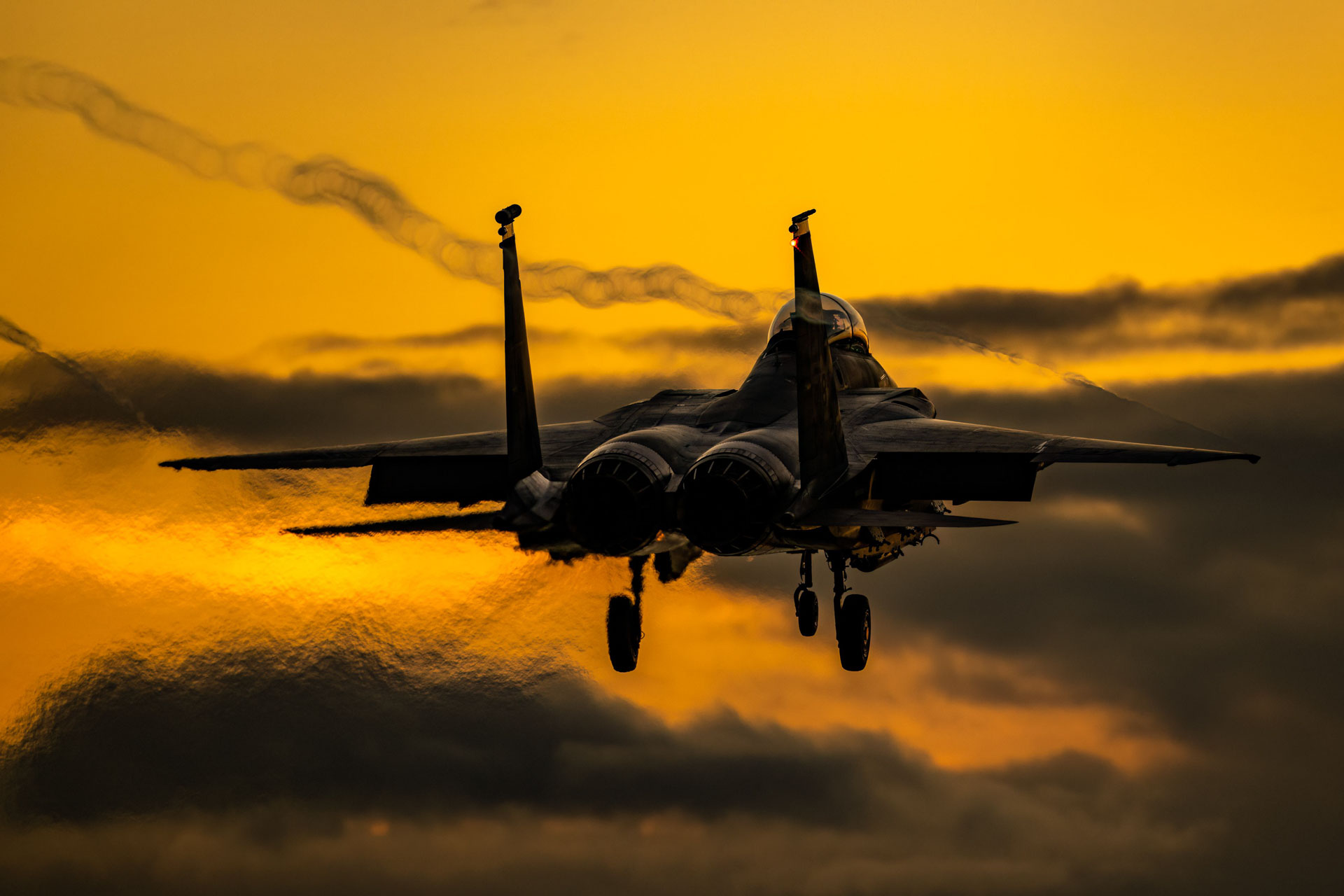 Fighter jet on landing approach against golden sunset